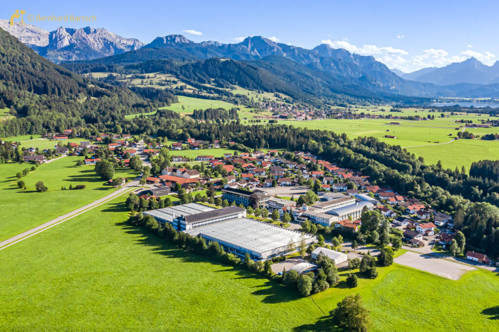 Der Ort Halblech am Fuße der Berge, aus der Vogelperspektive mit der Firma Bihler im Vordergrund, Drohnenfoto vom Fotograf und Webdesigner Bernhard Bartsch